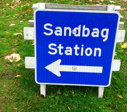 Sandbag Station standing sign with an arrow