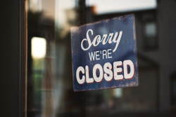 A sign that states "Sorry we're closed" hangs in the window of a store.
