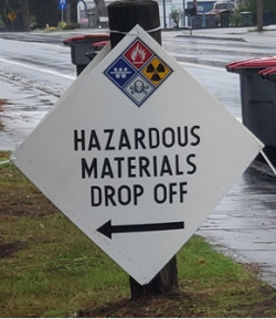 White, diamond-shaped sign with text that says Hazardous Materials Drop off