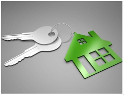 Picture of two silver keys attached to a green key chain in the shape of a house. 