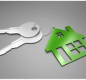 Picture of two silver keys attached to a green key chain in the shape of a house. 